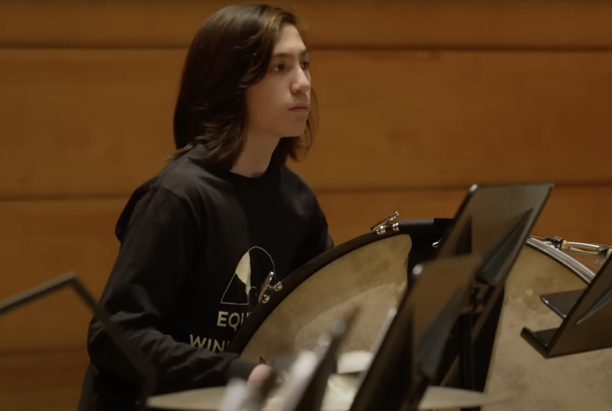 PLAYING IN HARMONY. Freshman Caleb Colton plays percussion in an improvised concert organized by Equity Arc Symphony and military band veterans. (Screencapture from 60 Minutes' full concert coverage).